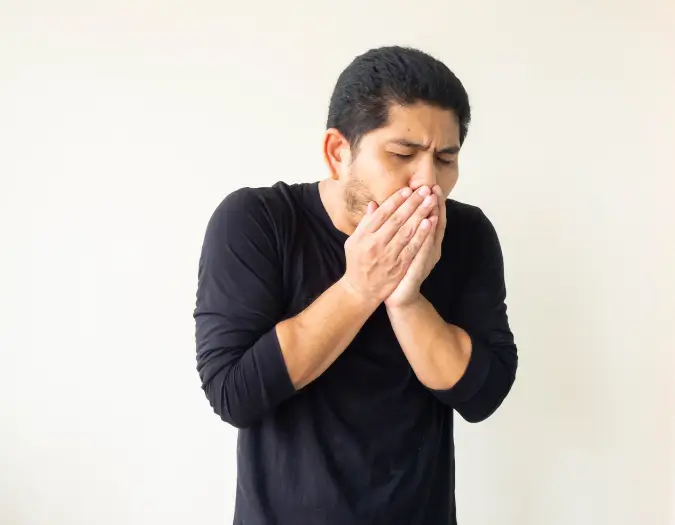 Patient holding chest while experiencing a persistent coughing episode caused by bronchitis at Dr. L Square Multispecialty Homeopathy Clinic